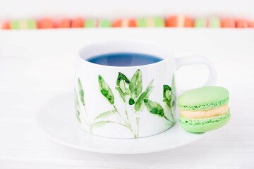 Porcelain cup of thai blue butterfly pea flower tea and green mint macaroon or macaron