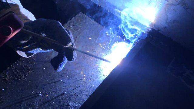 Process of electric welding of metal structures. Bright flames, smoke and sparks. Master in work gloves.