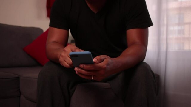 Young latin man talking on the phone at home and smiling. Latin American man having a phone call sitting on the Sofa at home. Lifestyle concept.