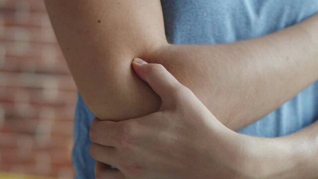 Woman massages sore elbow, closeup. Woman pulled ligaments on her elbow and now rub them. Female pulled muscles on arm