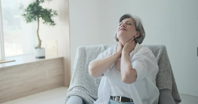 Elderly mature old woman stretches her neck, relieving herself of stress and relaxing while thinking about pleasant things. Smiling senior lady resting after completing business, reclining back