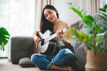 Asian woman playing music by guitar at home, young female guitarist musician lifestyle with...