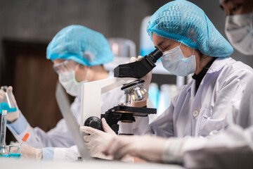 scientist looking through scientific microscope lense in laboratory, scientist doing research in...