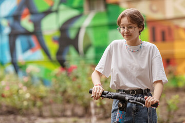 teen girl, brunette with glasses on a scooter, on a city street, on a clear sunny day