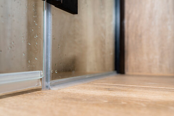 Seals in the lower part of the thresholdless shower enclosure, visible water drops.
