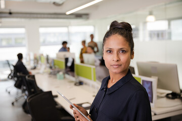 Portrait of confident businesswoman in open plan office