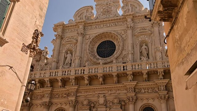 Lecce, Puglia, Italy. August 2021. The Basilica of Santa Croce is the finest example of the Lecce Baroque. The tilt footage highlights the richness of the facade details. Beautiful summer day.