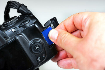 Photographer inserting or removing a blue memory card into the slot in the camera