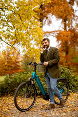 Plakat Young man with electric bicycle in the autumn park