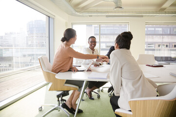 Happy business people touching hands, celebrating success in conference room