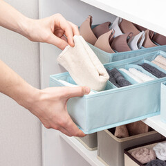 Man or woman sorts laundry. Organizer for wardrobe. Concept of order in house. Square