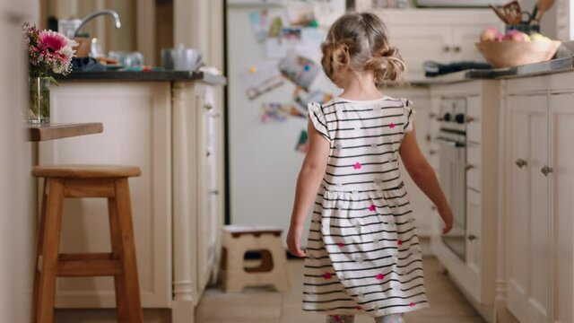 happy little girl taking cookie sneaky child stealing biscuit in kitchen at home