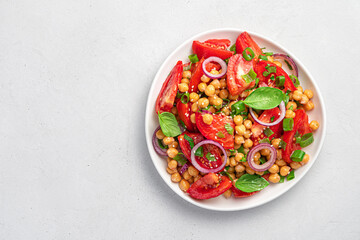 Salad with chickpeas and tomatoes on a gray background.