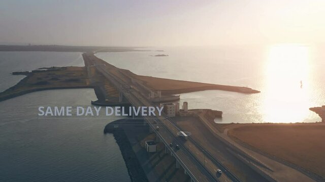 Aerial view of a truck with SAME DAY DELIVERY infographics driving along the highway across the sea