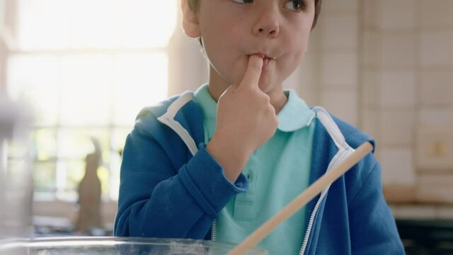 happy little boy eating leftover cookie dough in kitchen enjoying delicious sweet taste licking fingers having fun on weekend