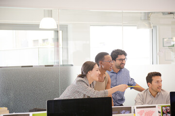 Business people brainstorming at computer in open plan office