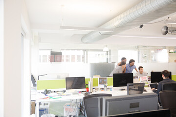 Business people brainstorming at computer in open plan office