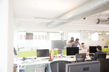 Business people brainstorming at computer in open plan office