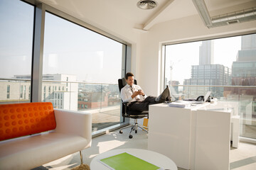 Businessman relaxing at desk in modern office