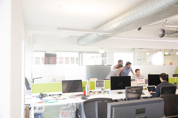 Business people brainstorming at computer in open plan office