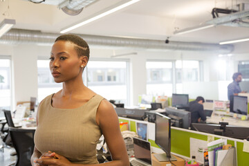 Portrait of smiling, confident businesswoman in open plan office