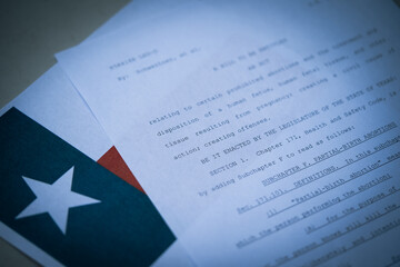 Blurred Close up view of Texas Abortion Law (TX SB8) next to the flag of Texas state. - obrazy, fototapety, plakaty