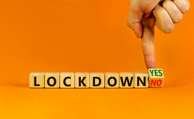 End of the covid-19 lockdown symbol. Doctor turns a cube and changes words 'lockdown yes' to 'lockdown no'. Beautiful orange background, copy space. Covid-19 pandemic lockdown concept.