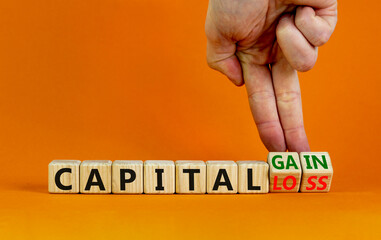 Capital loss or gain symbol. Businessman turns cubes and changes words 'capital loss' to 'capital gain'. Beautiful orange background. Business and capital loss or gain concept. Copy space.