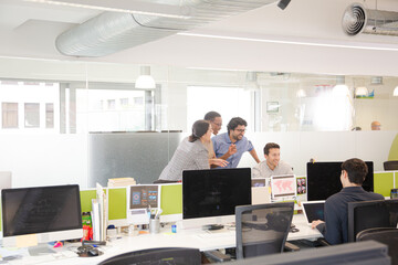 Business people brainstorming at computer in open plan office