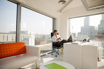 Naklejka na ściany i meble Businessman relaxing at desk in modern office