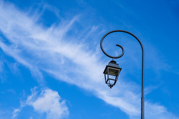 Fototapeta na wymiar Lantern on a blue sky background. Feathery clouds. Copy space. 