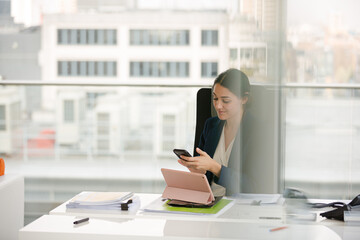 Businesswoman using smartphone and tablet computer at desk