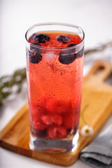 Tall glass with red fruits juice on ice