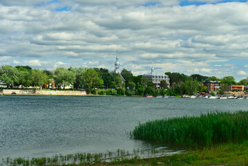 The marina of Boucherville at islands of Boucherville national park in Lawrence (Laurent) River, Montreal, QC on a cloudy summer day. The trees and grass on the river banks.