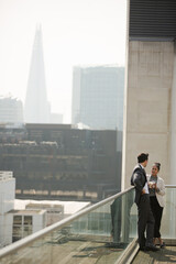Fototapeta premium Businessman and businesswoman enjoying coffee on balcony, talking