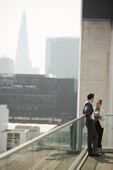 Fototapeta premium Businessman and businesswoman enjoying coffee on balcony, talking