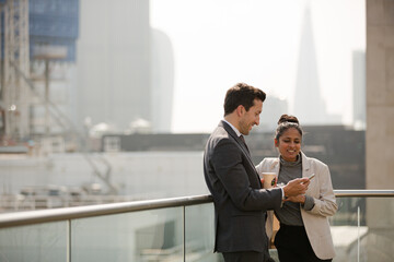 Businessman and businesswoman enjoying coffee on balcony, talking