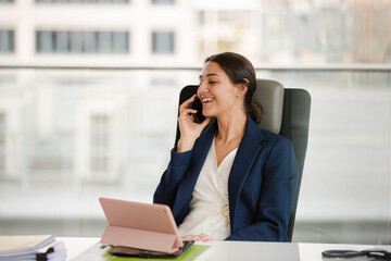 Businesswoman talking on cell phone and using tablet computer at desk