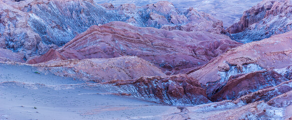 Panoramic image of the barren desert landscape with bare rocks in the Moon valley (Valle de la Luna) in the vicinity of San Pedro de Atacama in the blue hour before sunrise