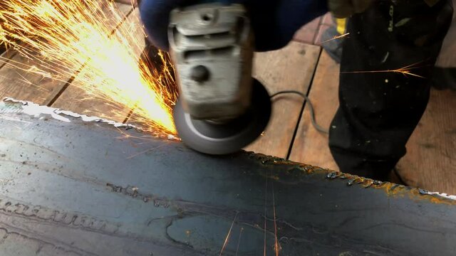 The process of electric grinding of metal structures. Bright flames and sparks. Master in work gloves.