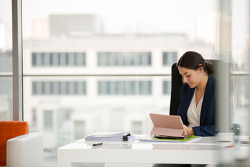 Businesswoman using smartphone and tablet computer at desk