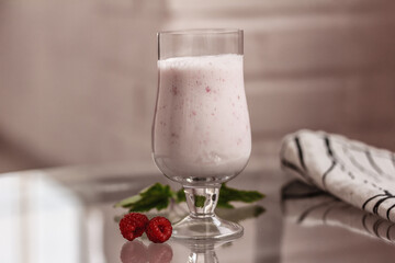 Raspberry Milkshake in a glass on a glass table. Tasty dessert, copy space