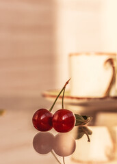 Two cherry berries, green leaf and a tee cup on glass background,. Sour cherry, cherry berry, copy space