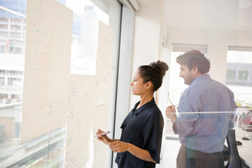 Fototapeta premium Business people discussing diagram sketches hanging on office window