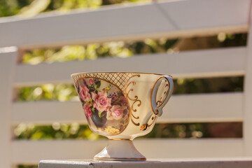 Floral teacup on white wooden background in the garden on a sunny day. Outdoor tea drinking , stock photo, copy space