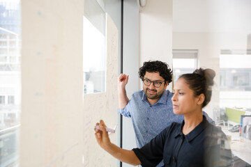 Business people discussing diagram sketches hanging on office window