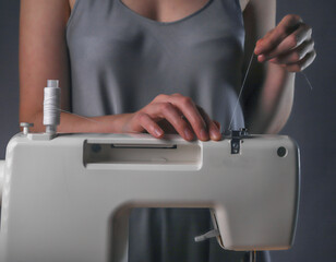 Naklejka premium Seamstress hands putting thread on sewing machine, work process.