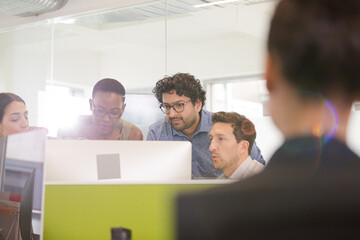 Business people brainstorming at computer in open plan office