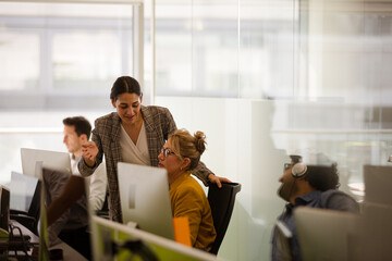 Business people talking at computer in open plan office