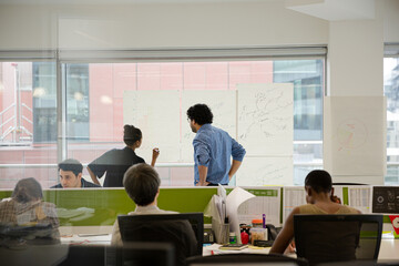 Business people discussing diagram sketches hanging on office window